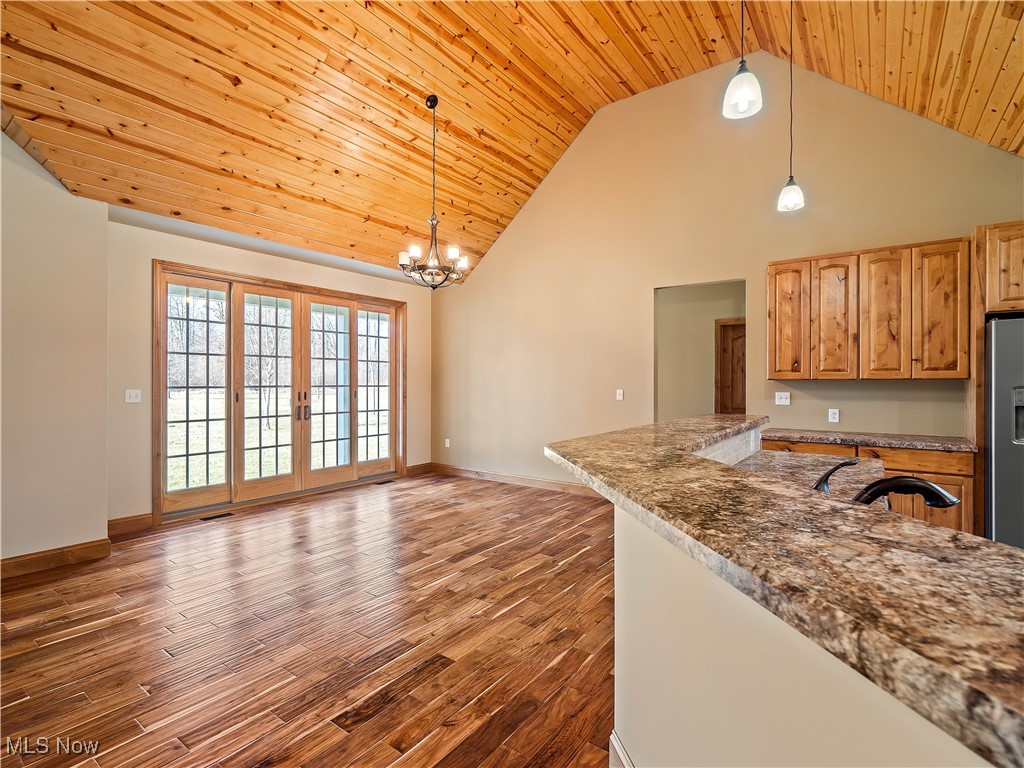 12740 Root Road Columbia Station, OH 44028 - Photo 23 of 47 Kitchen with a notable chandelier, high vaulted ceiling, stainless steel refrigerator with ice dispenser, dark wood finished floors, and wood ceiling