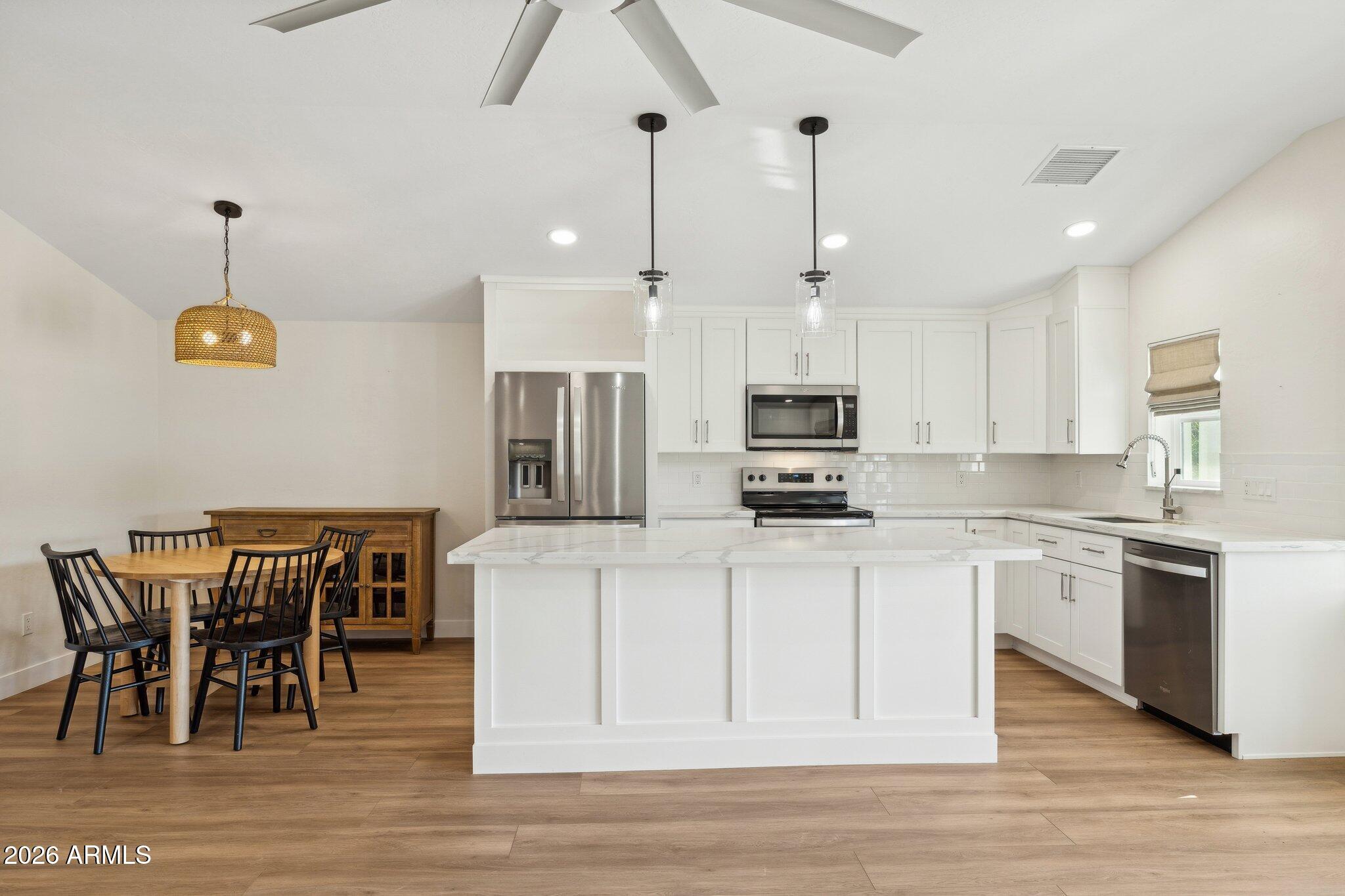 16226 East Fairview Street Gilbert, AZ 85295 - Photo 36 of 59 a kitchen with stainless steel appliances granite countertop a stove top oven a sink a dining table and chairs with wooden floor