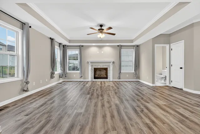 an empty room with wooden floor fireplace and windows
