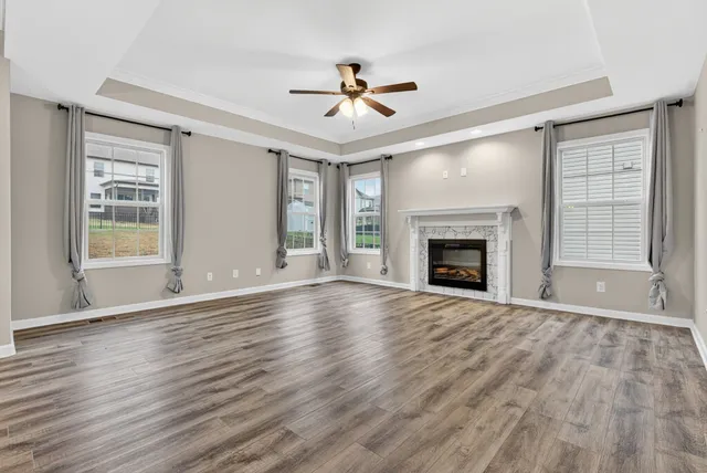 a view of an empty room with wooden floor fireplace and a window