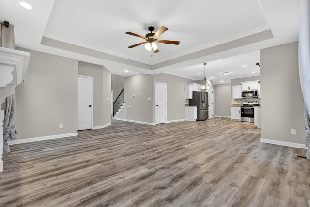 a open kitchen with stainless steel appliances granite countertop a refrigerator oven stove a sink dishwasher and white cabinets with wooden floor