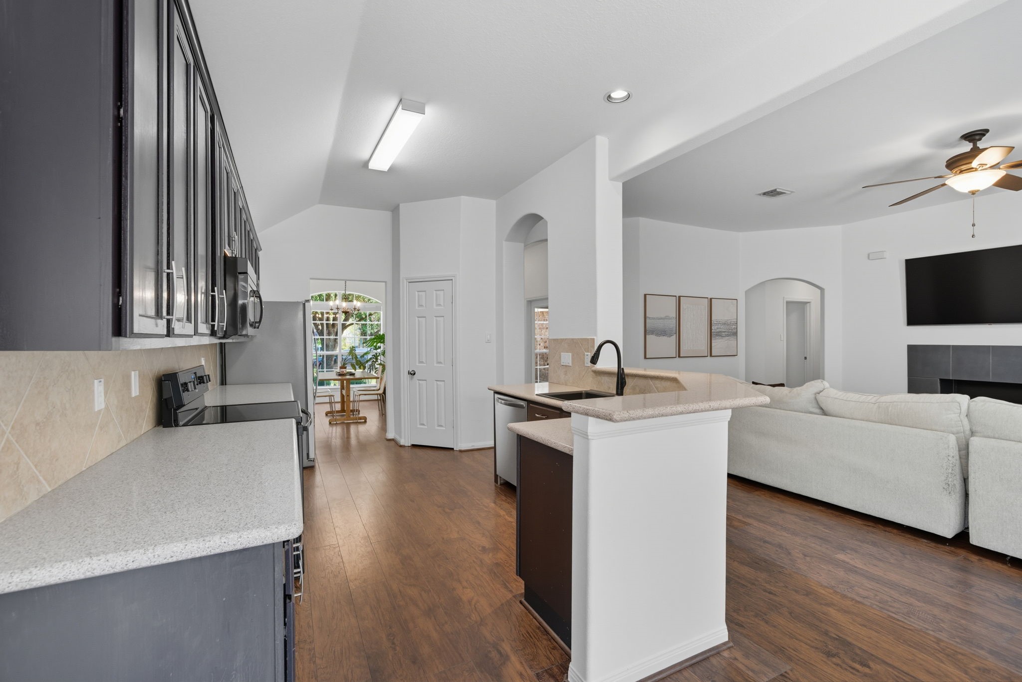 3323 Rollingwood Montgomery, TX 77356 - Photo 13 of 43 a large white kitchen with a stove a sink a refrigerator and a dining table with wooden floor