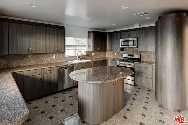 a kitchen with stainless steel appliances a sink a stove a refrigerator cabinets and a window