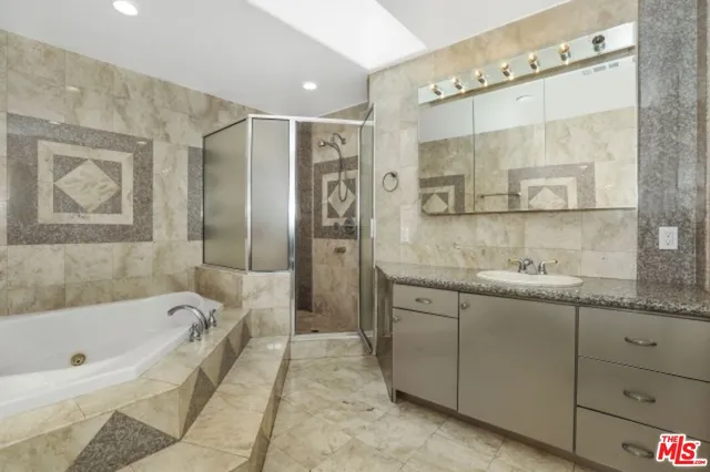 a bathroom with a granite countertop bathtub sink vanity and mirror