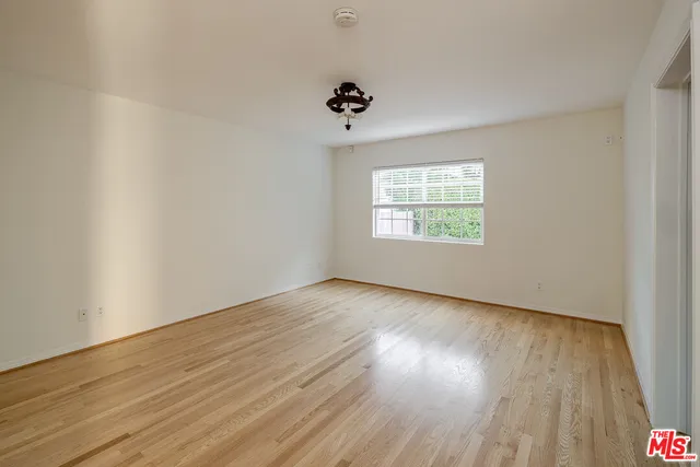 an empty room with wooden floor ceiling fan and windows