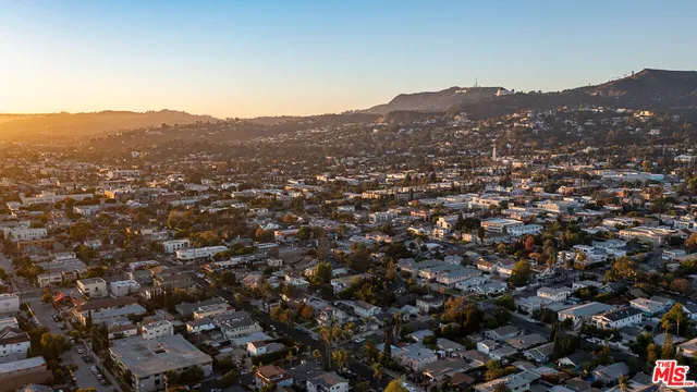 an aerial view of residential houses with city and mountain view in back