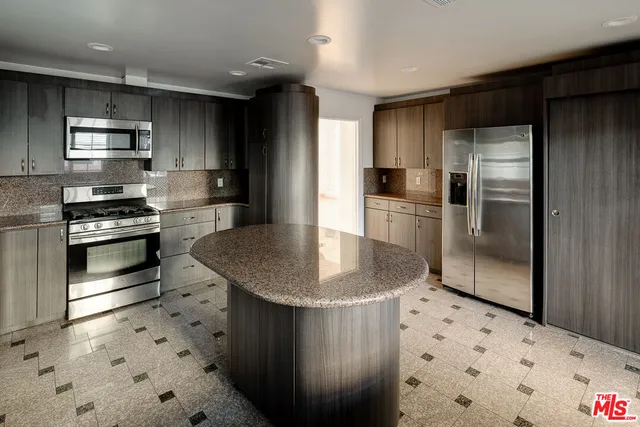 a kitchen with stainless steel appliances granite countertop a sink a stove a refrigerator and cabinets