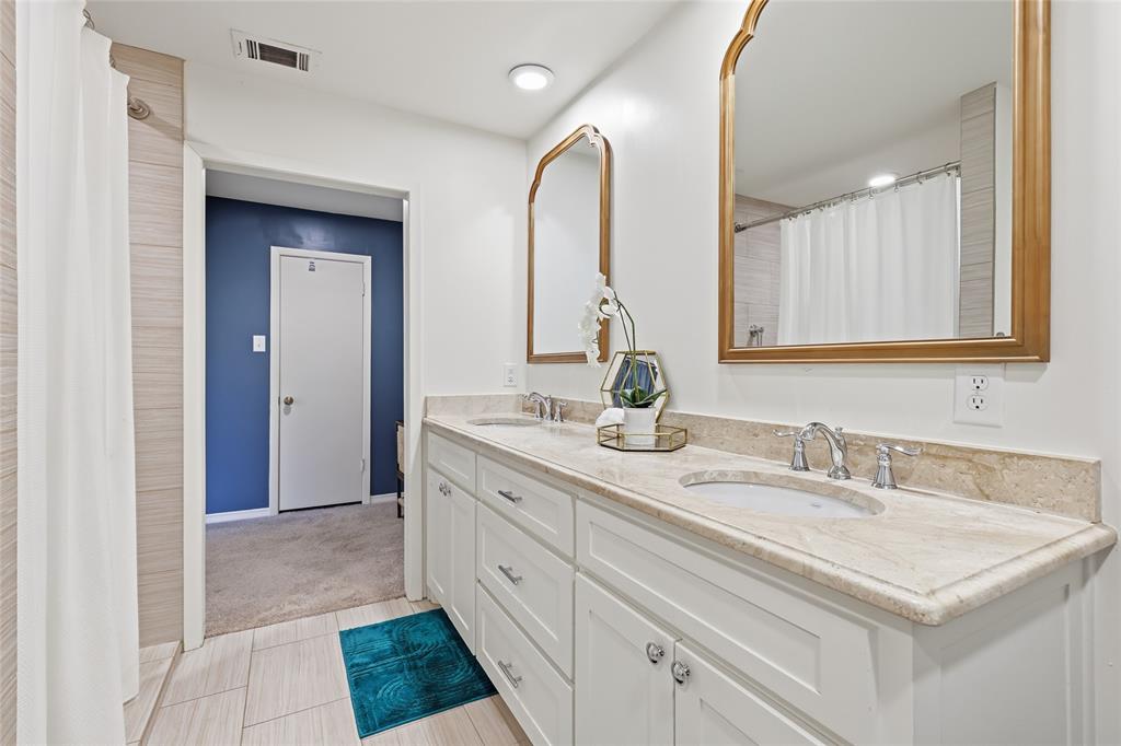 823 Ridgecrest Circle Denton, TX 76205 - Photo 21 of 40 Bathroom vanity featuring dual under-mount sinks, a light-toned stone countertop, and two ornate gold-framed mirrors