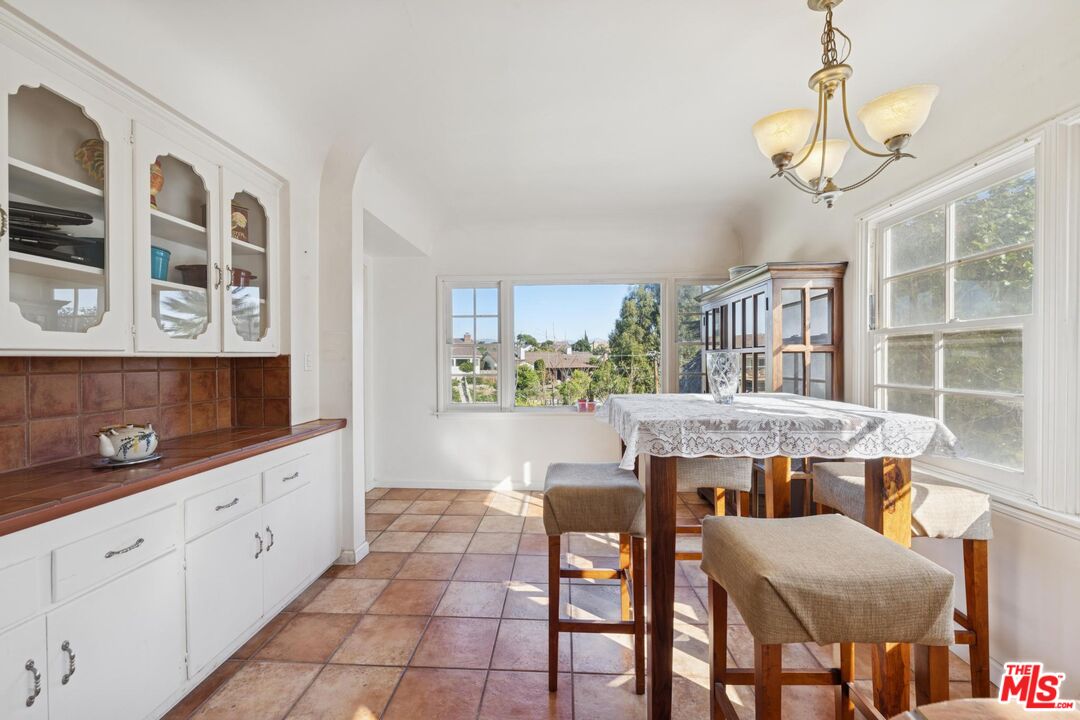 5002 Valley Ridge Avenue View Park, CA 90043 - Photo 12 of 44 a dining room with stainless steel appliances kitchen island granite countertop a table chairs in it and wooden floors