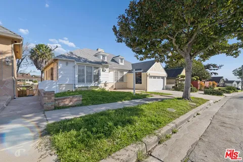 a front view of a house with a yard and potted plants