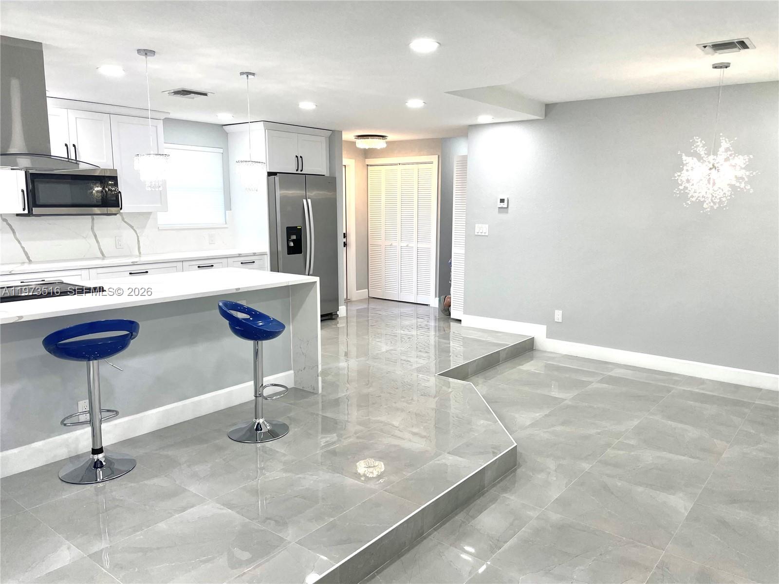 1280 West Camino Real, Unit 1280 Boca Raton, FL 33486 - Photo 3 of 26 a kitchen with stainless steel appliances kitchen island granite countertop a sink a stove a refrigerator cabinets and dining table
