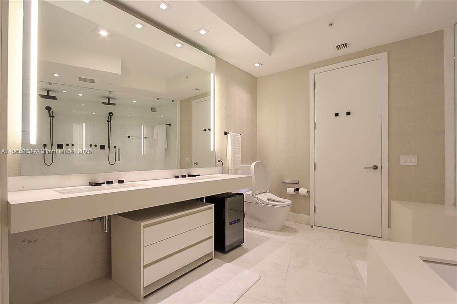 18555 Collins Avenue, Unit 4605 Sunny Isles Beach, FL 33160 - Photo 21 of 40 a bathroom with a sink a toilet and a large mirror