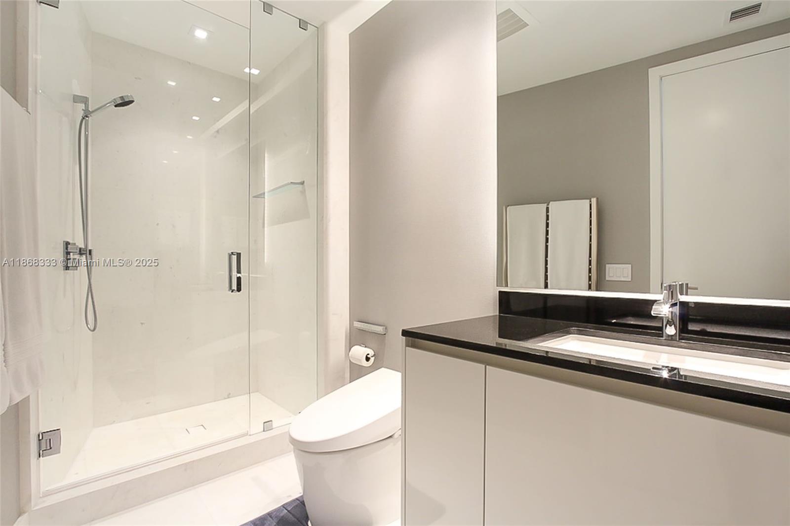 18555 Collins Avenue, Unit 4605 Sunny Isles Beach, FL 33160 - Photo 37 of 40 a bathroom with a granite countertop sink a toilet a mirror and shower