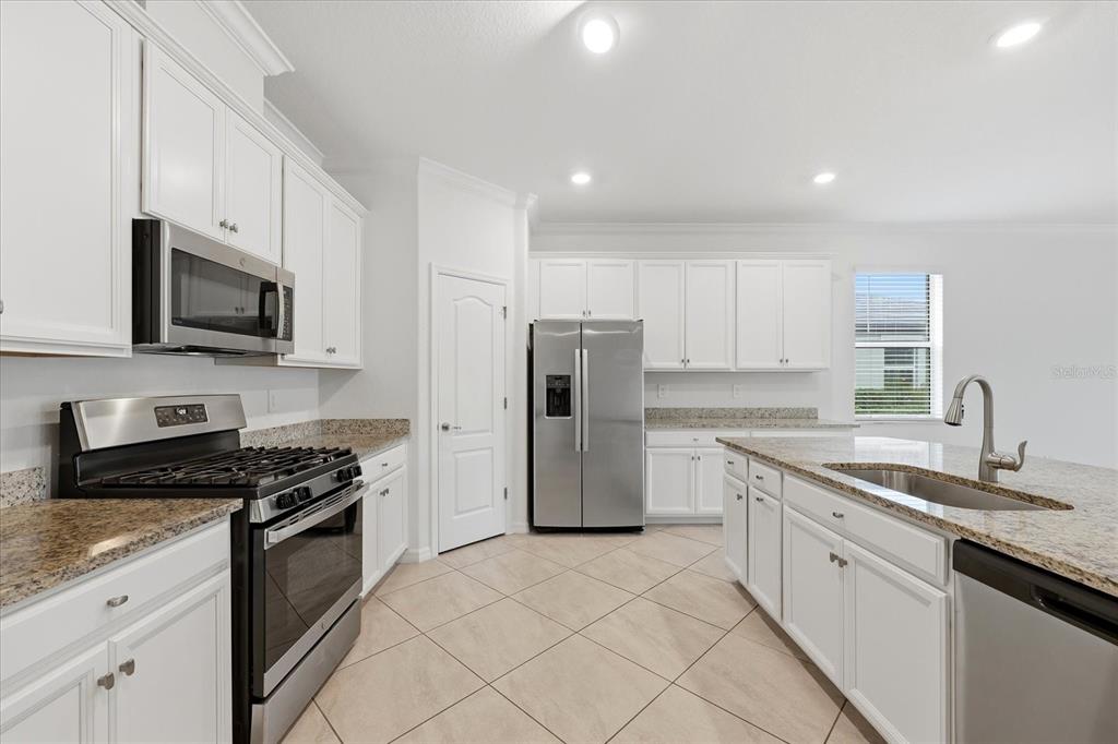 2607 Avolet Court Lakewood Ranch, FL 34211 - Photo 11 of 56 a kitchen with stainless steel appliances granite countertop a stove a sink and a refrigerator
