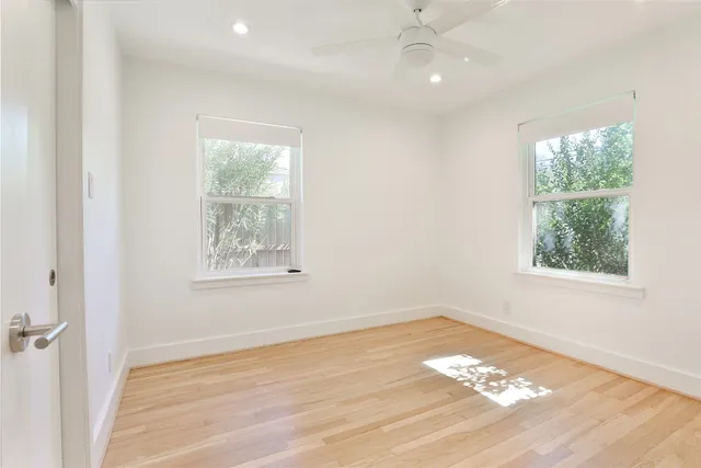 an empty room with wooden floor and windows