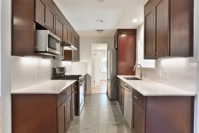 a kitchen with stainless steel appliances granite countertop a sink stove and refrigerator