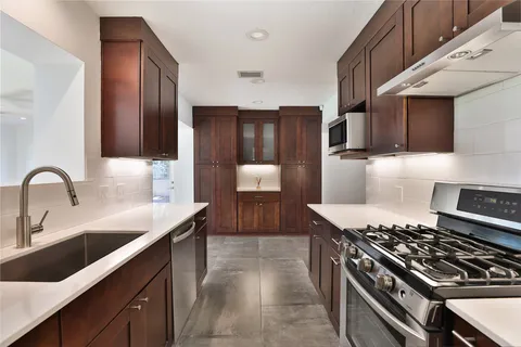 a kitchen with granite countertop a sink stove and cabinets