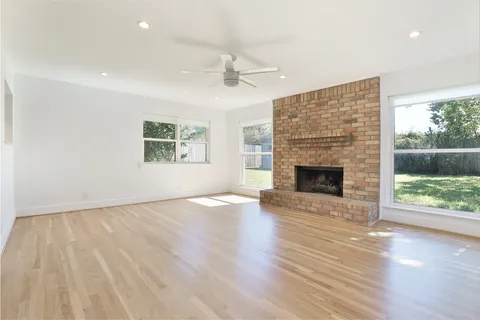 an empty room with wooden floor fireplace windows and wooden floor