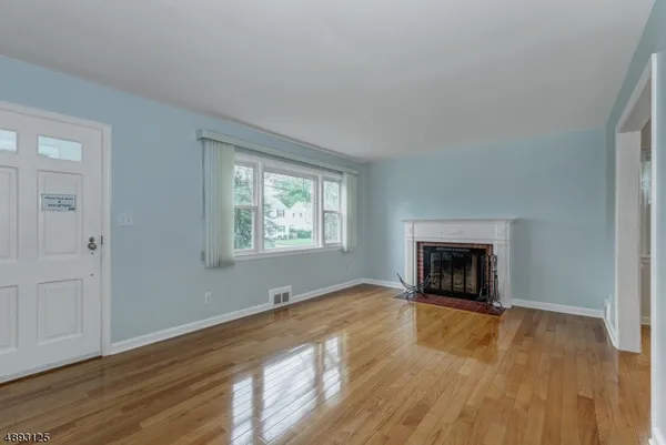 an empty room with wooden floor fireplace and windows