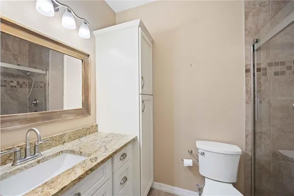 a bathroom with a granite countertop sink toilet and shower