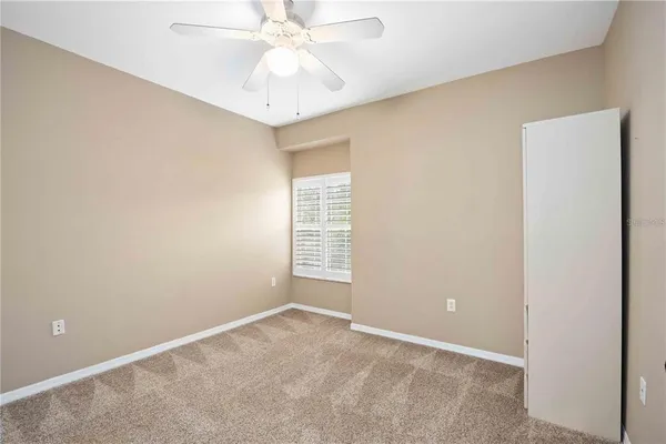 an empty room with a chandelier fan and windows