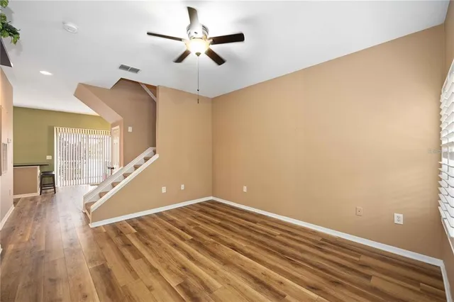 a view of a room with wooden floor and ceiling fan