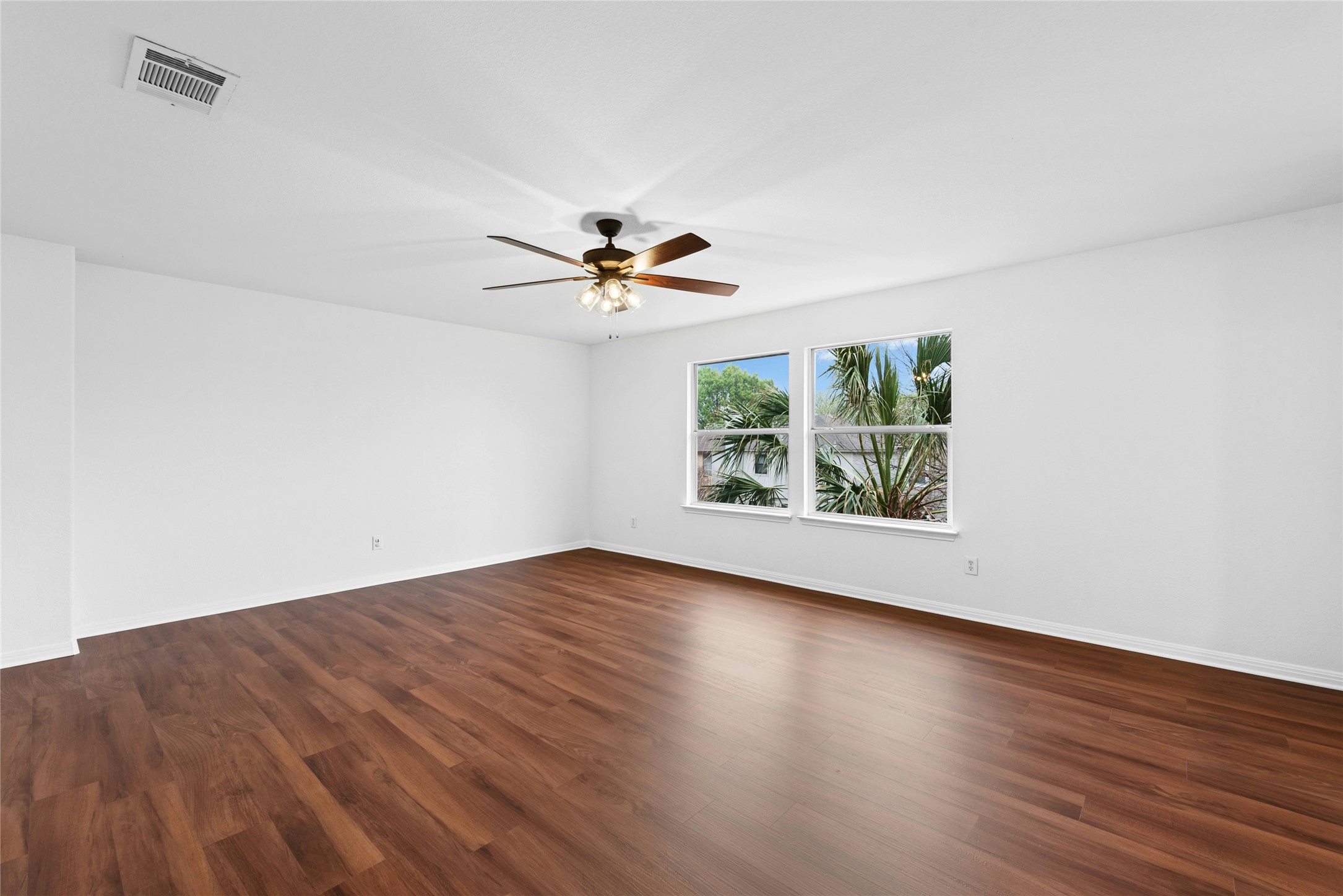 813 Caribou Ridge Trail Pflugerville, TX 78660 - Photo 33 of 39 Empty room with dark wood finished floors and ceiling fanSpacious loft or flex living area with warm luxury flooring, abundant natural light, and large windows framing a beautiful palm tree view.