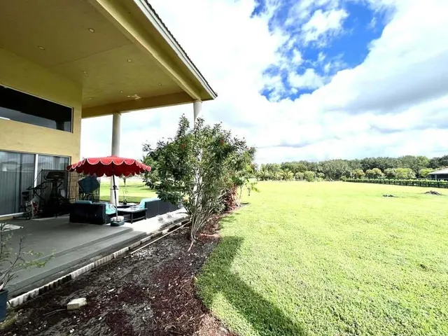 a view of a patio with a table and chairs under an umbrella