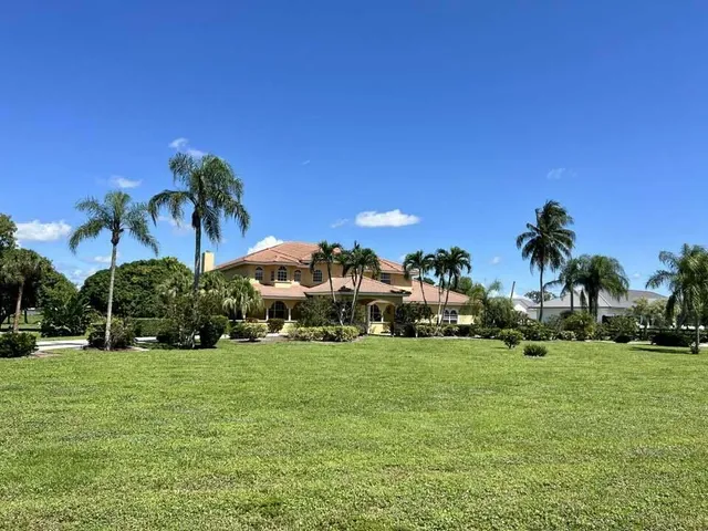 a view of a house with a yard and palm trees
