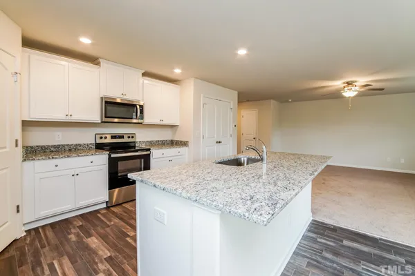 an empty room with a chandelier fan and windows
