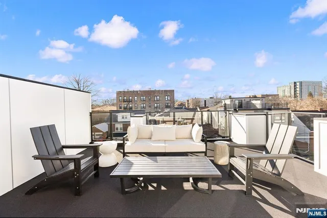 a living room with couches a coffee table and chairs with the view of city