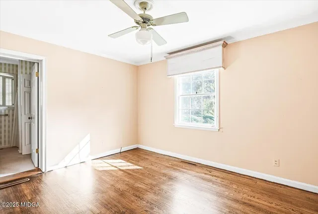 an empty room with wooden floor fan and windows