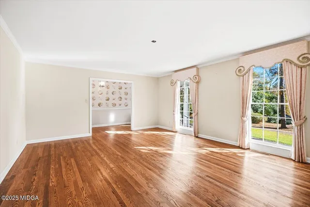 a view of an empty room with a window and wooden floor