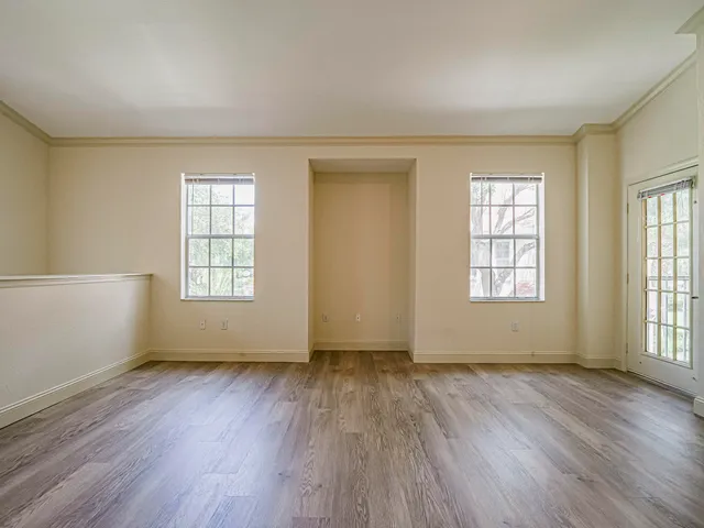 an empty room with wooden floor and windows with curtains view