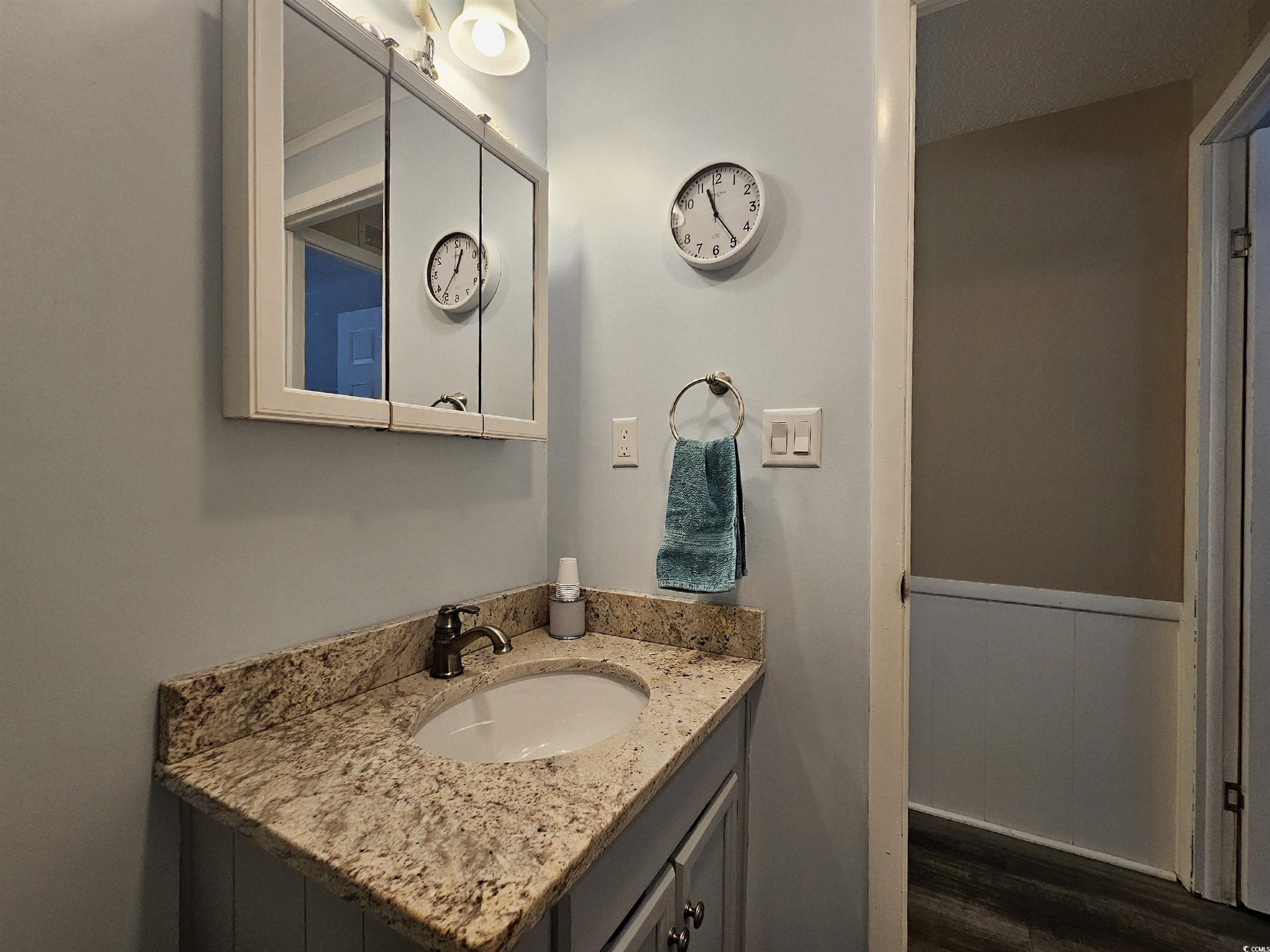 355 Meadowlark Surfside Beach, SC 29575 - Photo 20 of 39 Bathroom featuring vanity, dark wood finished floors, and a wainscoted wall