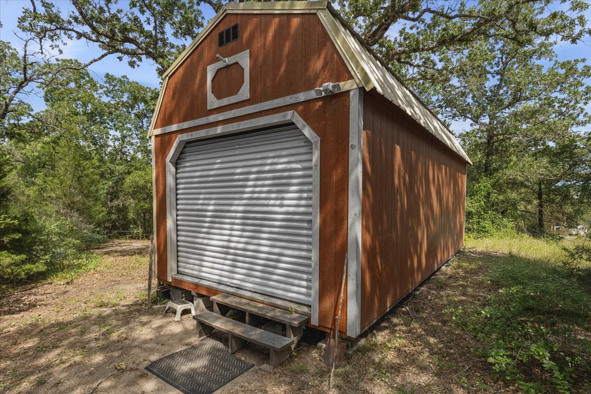 1705 Makinson Road West Point, TX 78963 - Photo 24 of 40 A well-maintained shed offers practical storage amidst a natural, wooded setting.