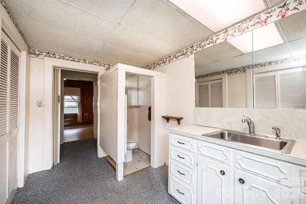 a bathroom with a granite countertop sink a toilet a mirror and shower