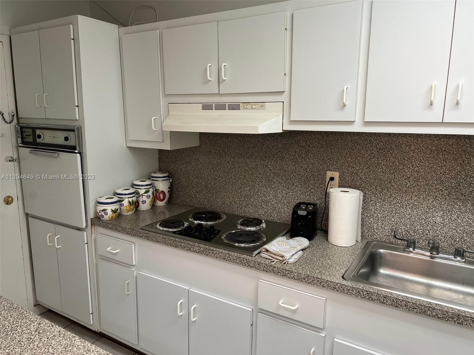 100 Lincoln Road, Unit 1001 Miami Beach, FL 33139 - Photo 13 of 62 a kitchen with white cabinets and sink