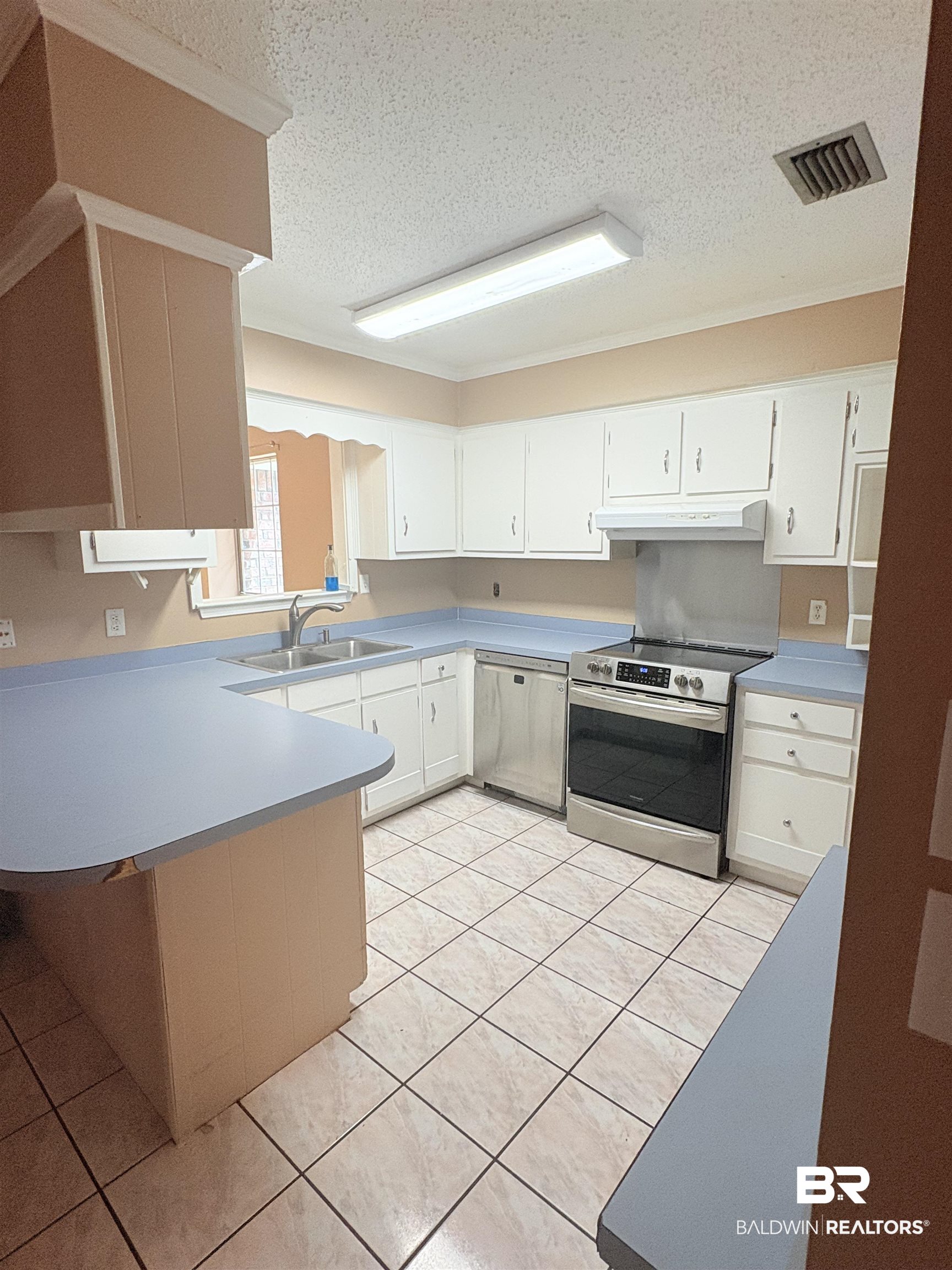 8070 Middle Ring Road Mobile, AL 36619 - Photo 5 of 26 Kitchen featuring a textured ceiling, appliances with stainless steel finishes, a peninsula, light countertops, and light tile patterned floors