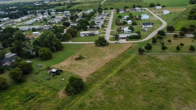 an aerial view of a residential houses with outdoor space and trees