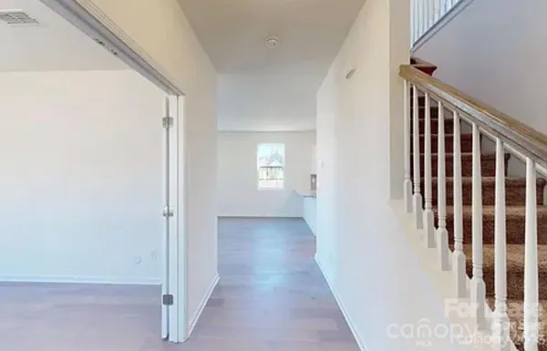 a view of a hallway with wooden floor and stairs