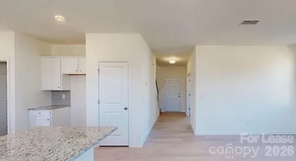 a view of a kitchen with white cabinets and a refrigerator