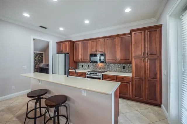 a kitchen with stainless steel appliances granite countertop a refrigerator a stove a sink a dining table and chairs with wooden floor