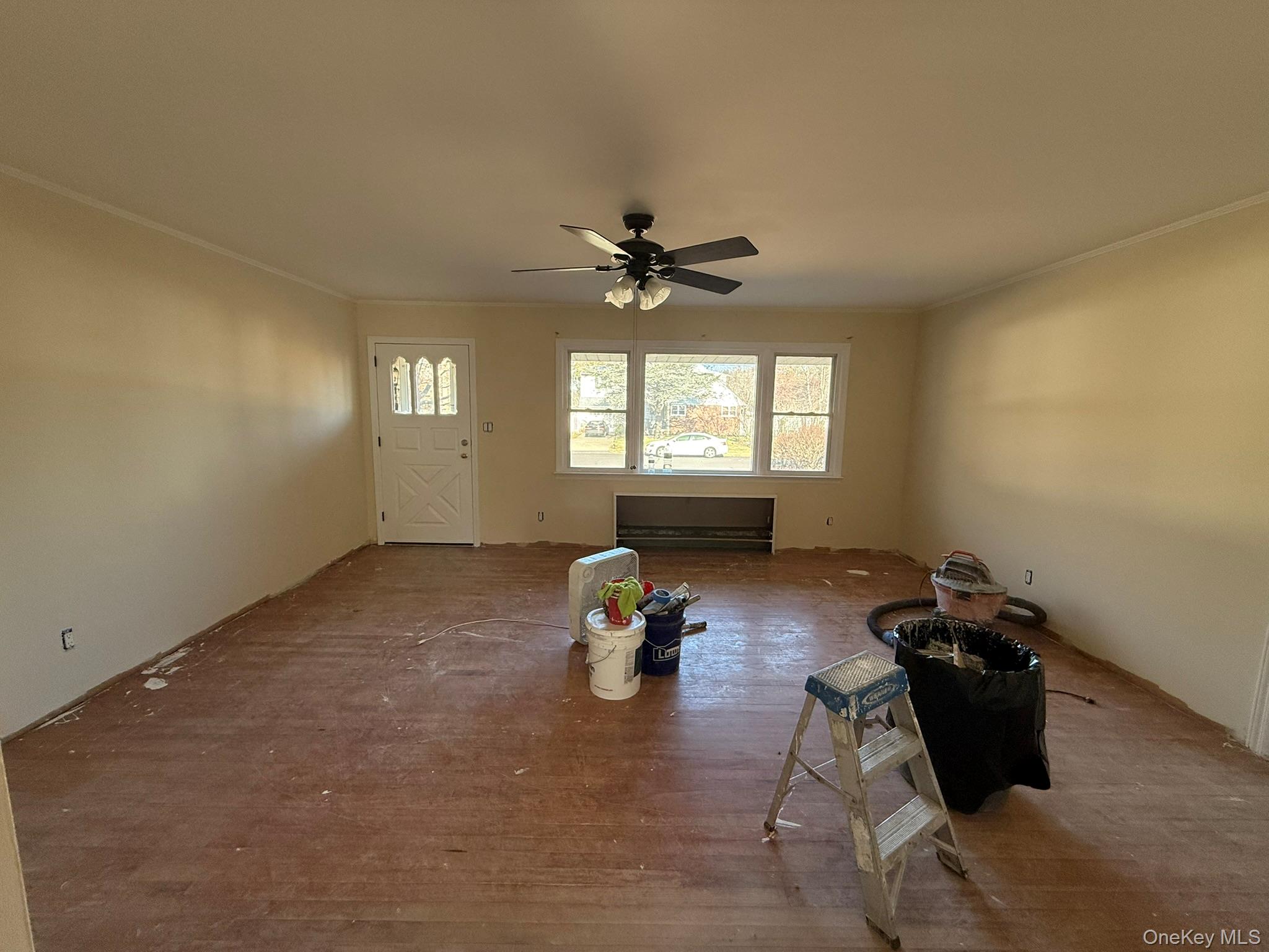Unfurnished living room with crown molding, a ceiling fan, and wood finished floors