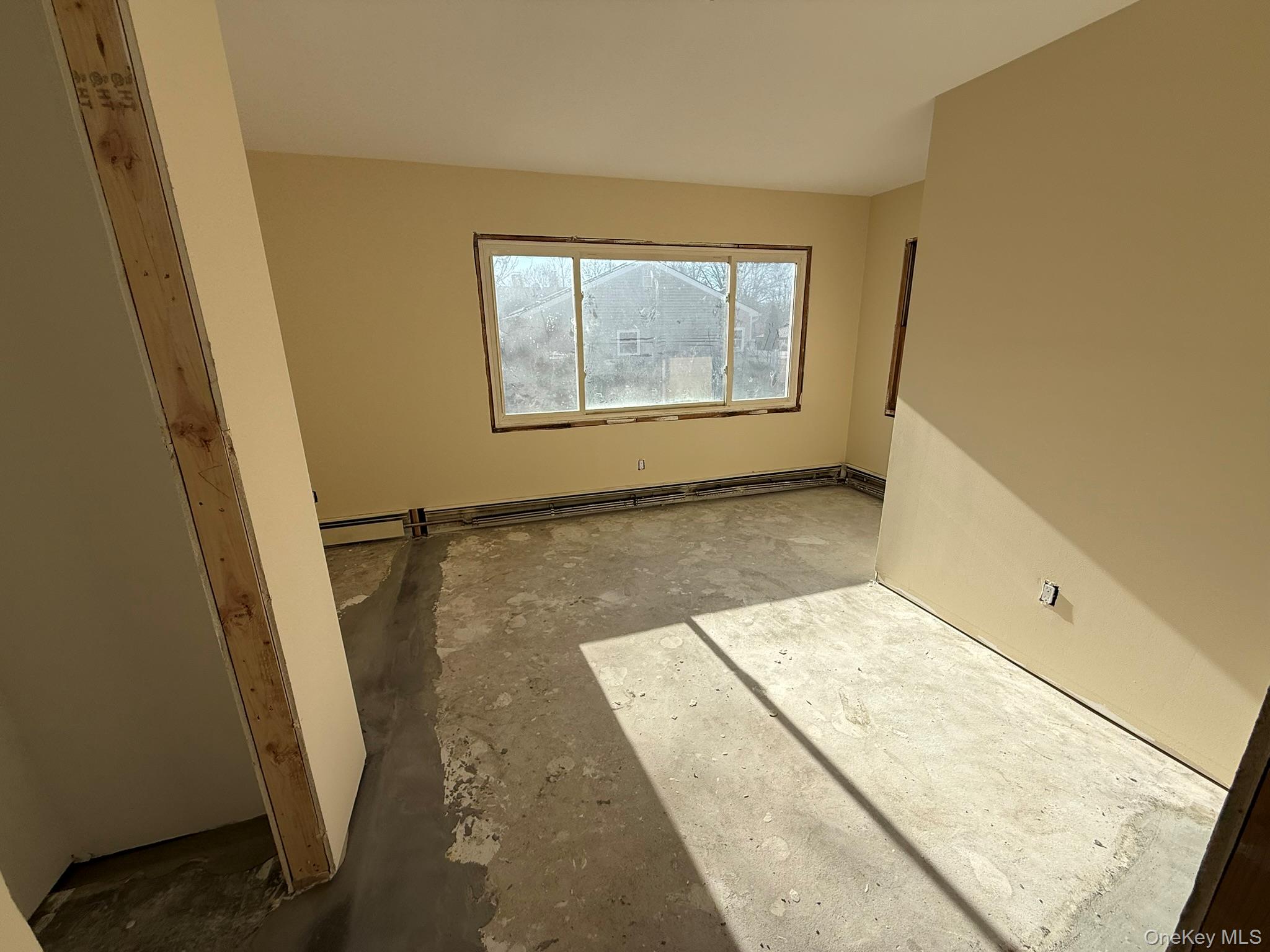 24 Poplar Place Bay Shore, NY 11706 - Photo 4 of 10 Unfurnished room with unfinished concrete flooring and a baseboard heating unit