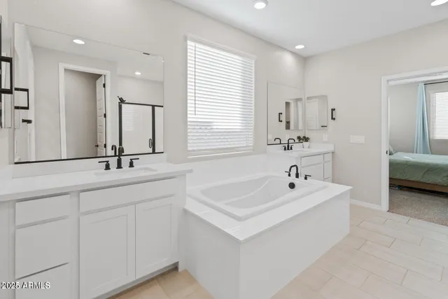 a spacious bathroom with a double vanity sink a mirror and a bathtub