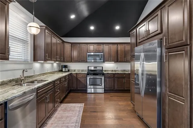 a large kitchen with granite countertop stainless steel appliances wooden cabinets a stove and a sink