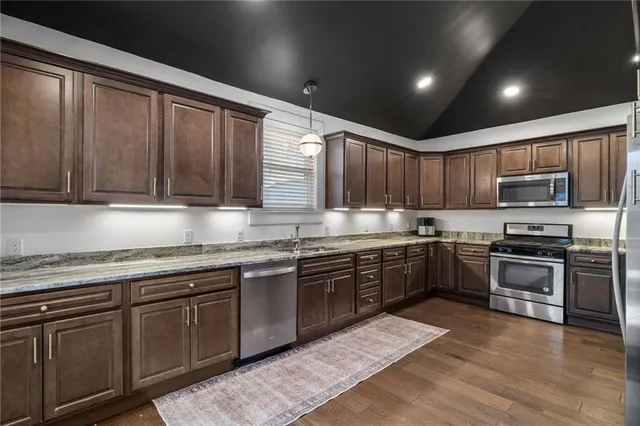 a kitchen with stainless steel appliances granite countertop wooden cabinets a stove top oven a sink and dishwasher