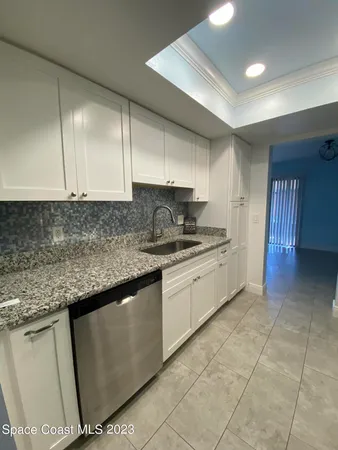 a kitchen with granite countertop a sink a stove top oven cabinets and a counter top space