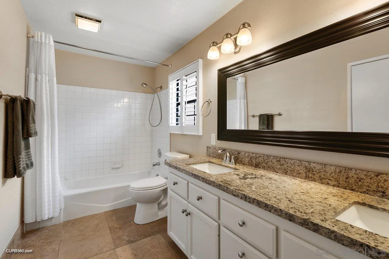 4579 54th Street San Diego, CA 92115 - Photo 23 of 39 a bathroom with a granite countertop sink a toilet a mirror and shower